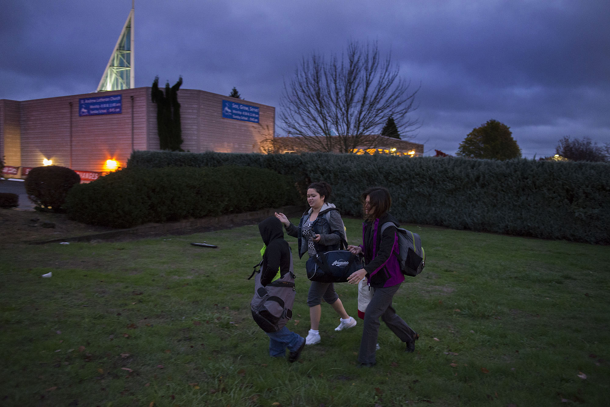 Johnny Pinaula, 7, from left, joins his sister, Shyanne Tanguileg, 16, and his mom, Donna Pinaula, as they leave St. Andrew Lutheran Church before sunrise to start their day Tuesday morning, Nov. 17, 2015 in Vancouver. (Amanda Cowan/The Columbian)